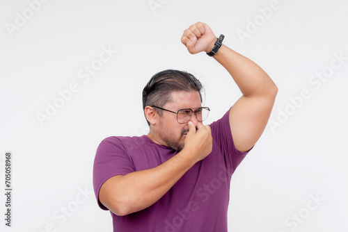 A middle aged man cover his nose from the strong smell emanating from his underarms. Bad body odor, forgotten to put deodorant. Isolated on a white background.