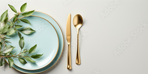 Golden cutlery arranged neatly on a white plate with a blue rim, adorned with green leaves