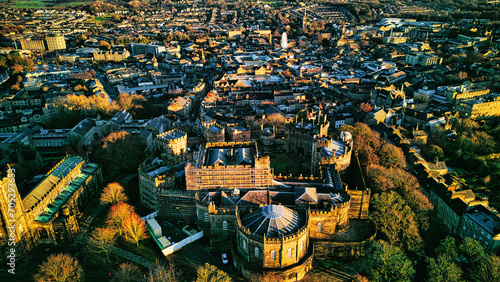 Aerial view of a historic city Lancaster at sunset with warm lighting highlighting architectural details and dense urban landscape.