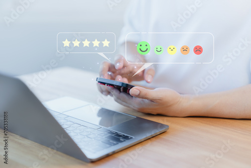 Male hand using a mobile phone with virtual screen on happy smile face icon to give satisfaction in service. Opinion rating very impressed. Assessment testimonial customer service and feedback concept