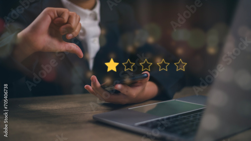Businesswomen chose a 1-star rating review in the survey on the virtual touch screen on smartphones. Bad review, bad service dislike bad quality, low rating, social media not good