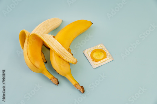 two bananas and a condom on blue background, sex concept