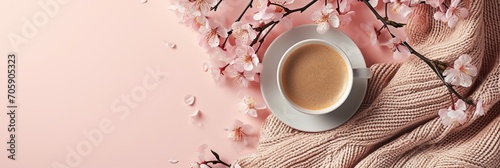 Cup of coffee on a pink knitted texture with cherry blossoms. Springtime cozy concept. Relaxation and leisure theme. Design for banner, invitation, greeting card. Flat lay composition with copy space