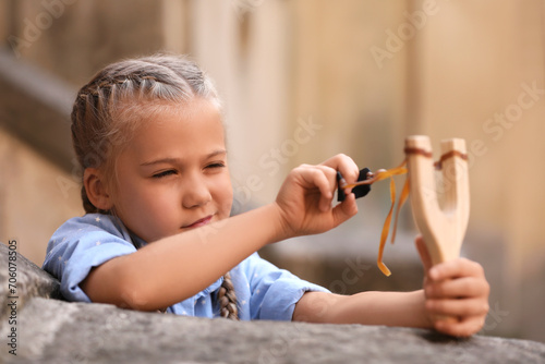 Cute little girl playing with slingshot outdoors