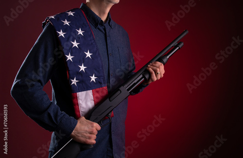 Armed citizen holding a shotgun with an American flag over his shoulder