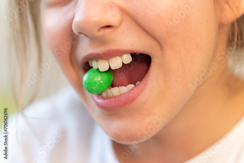 green round candy in the teeth of a young teenage girl. Addiction of sweets and candies. The harm of sweets for teeth.