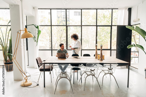 Young multiracial people interacting in spacious bright co working office with big window,