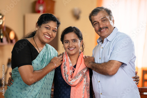 Happy smiling Middle class parents with daughter looking camera at home - concept of family bonding, relationship and generations