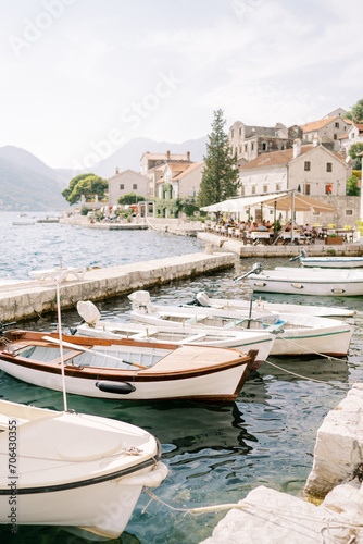 Row of fishing boats moored at the Perast pier against the backdrop of ancient stone houses at the foot of the mountains. Montenegro