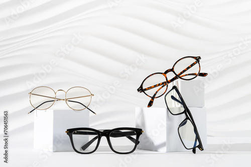 Trendy eyeglasses of different design on podiums on white background. Minimal still life. Copy space. Eyewear and spectacles sale concept. Optic shop promotion banner. Modern Eyewear fashion