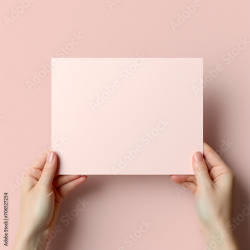fotografia de estilo mockup con detalle de hoja de papel de tonos rosados, sostenida por unas manos, sobre fondo neutro