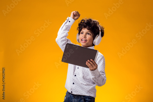 Child boy using digital tablet and headphones and playing video game. Leisure and gadget addiction concept