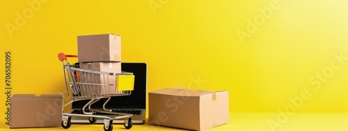 Shopping cart, cardboard boxes and laptop, online shopping concept, technology, yellow background.