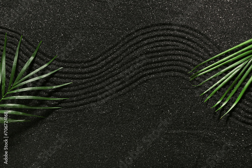 Tropical leaves on dark sand with lines, top view. Zen concept