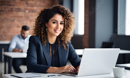 Curly-haired girl smiles while working on a laptop