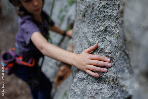 rock climber's hand close-up. child rock climber in a blue protective helmet overcomes the route in the mountains. children's sports in nature.