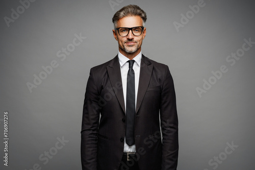 Adult confident attractive serious calm employee business man corporate lawyer wearing classic formal black suit shirt tie work in office look camera isolated on plain grey background studio portrait.