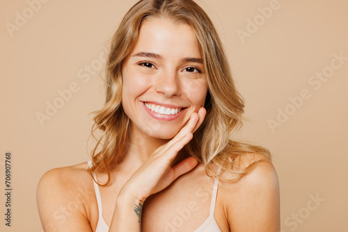 Close up young nice lady woman with slim body perfect skin wears nude top bra lingerie stand put hand touch face look camera isolated on plain pastel light beige background Lifestyle diet fit concept