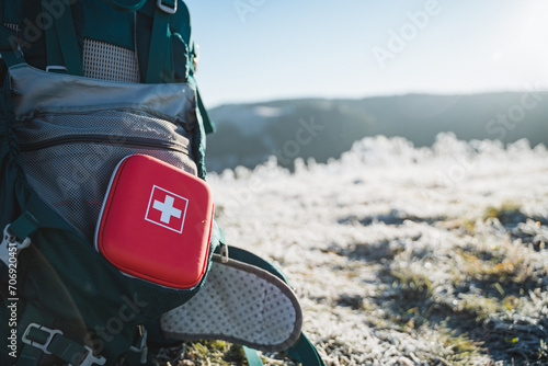 A red first aid kit is on the backpack, tourist equipment.