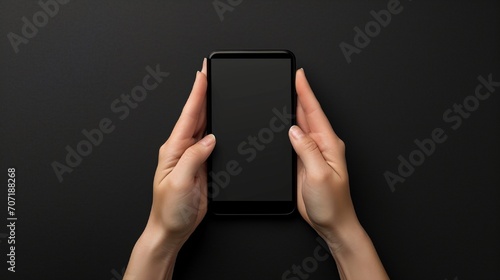 A top-down perspective capturing hands with a mobile mockup against a black background, the high-definition image highlighting the realistic texture and sleekness of the device