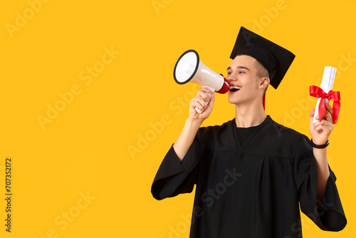 Male graduate student with diploma shouting into megaphone on yellow background