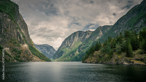Moody fjord with mountains and waterfall of Aurlandsfjord at Gudvangen in Norway, dark clouds in the sky.