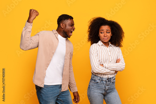 Angry black man yelling, woman upset on yellow backdrop