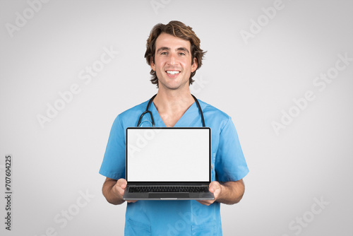 Happy male nurse presenting laptop with white blank screen