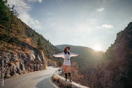 Woman road mountain. A woman in a white sweater, black boots and a hat walks along a winding alpine path between the mountains at sunset in late summer. The concept of travel.