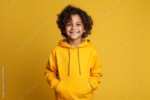 Portrait of a smiling african american little girl in yellow hoodie standing over yellow background