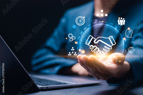 Businessmen use laptop with virtual handshake icon for business joint venture concept, data exchange customer connection, teamwork and successful business.