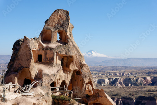 View of an old troglodyte settlement in Uchisar with Mount Erciyes in the background. Travel concept for Cappadocia.