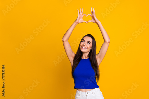 Photo of funky dreamy lady dressed blue top showing arms heart looking empty space isolated yellow color background