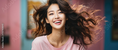 Beautiful smiling asian woman in pink t-shirt with flying hair