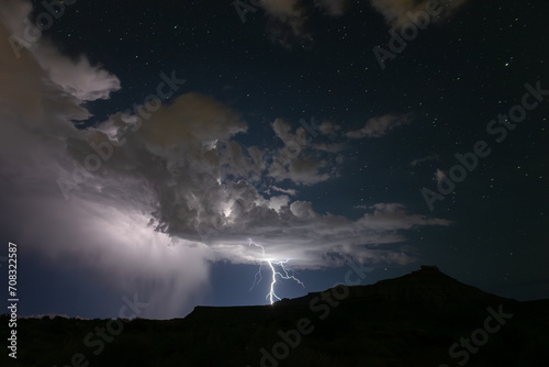 A summer monsoon storm delivers one of it's last lightning bolts as it passes into the distance beyond Gooseberry Mesa in Southern Utah, USA, leaving a starry night sky washed clean of dust.