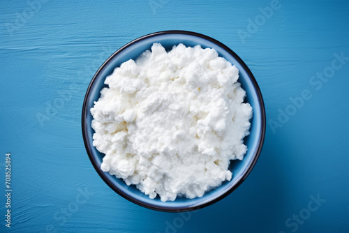 a bowl with white cottage cheese on a blue background, top view. healthy food, fermented milk product. curd.