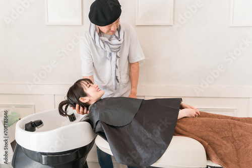 美容室のシャンプー台でシャンプーする女性と美容師・スタイリスト 