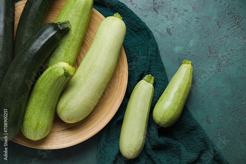 Plate with fresh zucchini on green background
