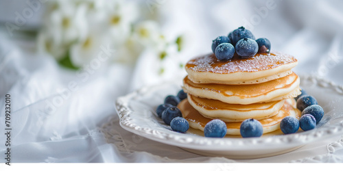 Fluffy tasty pancakes with blueberries on a plate in bright daylight. Rustic shabby chic feel. Pancake Day. Banner with empty space for text.