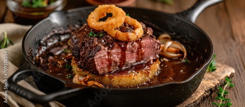Roast beef with onion rings and Swiss rosti, served in a skillet with brown sauce.