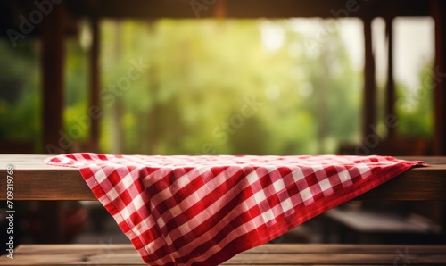 table covered with a white and red checkered tablecloth against the background of a window as a basis for the presentation of the subject