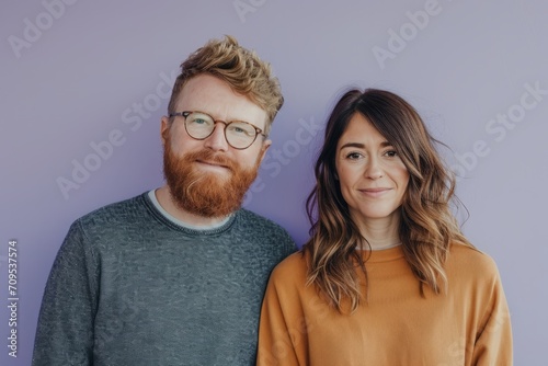 Portrait of a young couple standing together against a purple background.