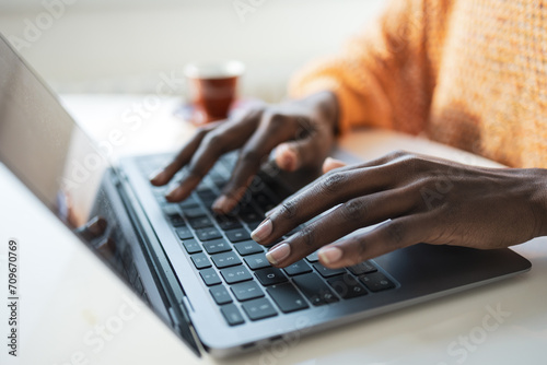 Anonymous female freelancer typing on laptop in home office