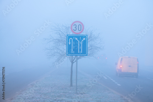 Traffic in fog, road signs and vehicle on the road