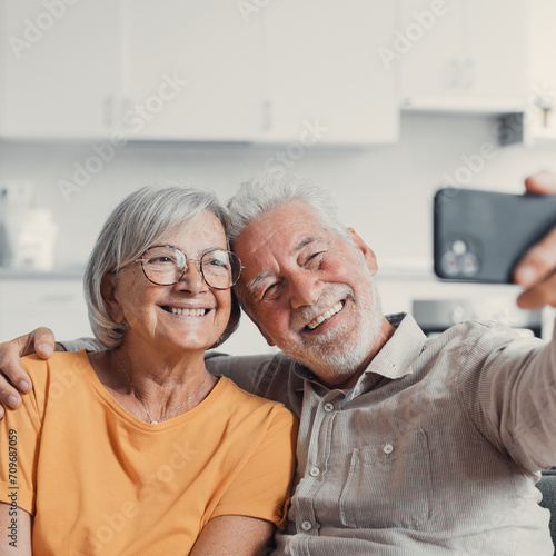 Happy old couple taking selfie on cellphone, smiling senior mature spouses middle aged wife and retired husband laughing holding phone make self portrait on smartphone camera, focus on mobile display.