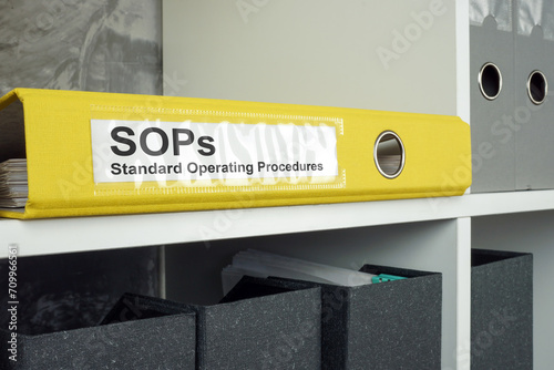 SOP Standard operating procedure concept. A yellow folder lies on an office shelf.