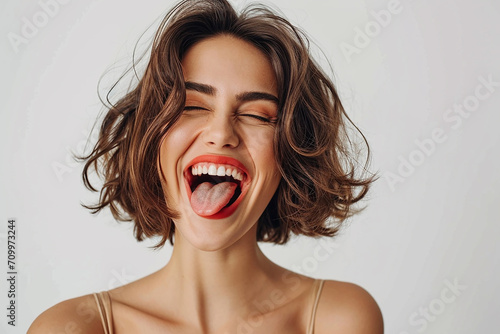 closeup shot of attractive young woman winking joyfully and showing tongue sassy on white isolated background