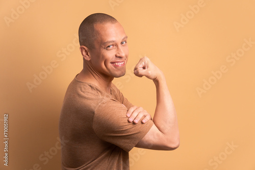 joyful brazilian man flexing arms in all beige colors. strong, power, proud concept.