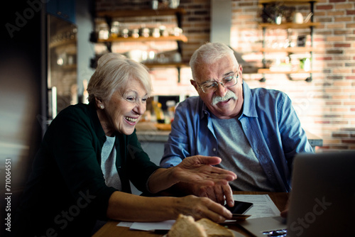 Senior couple doing home financials in the kitchen with laptop