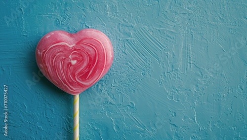 piruleta de fresa con forma de corazón sobre fondo de muro color azul estocado